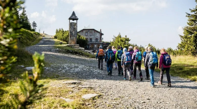 Skupina turistů kráčí po cestě k chatě na Šeráku.