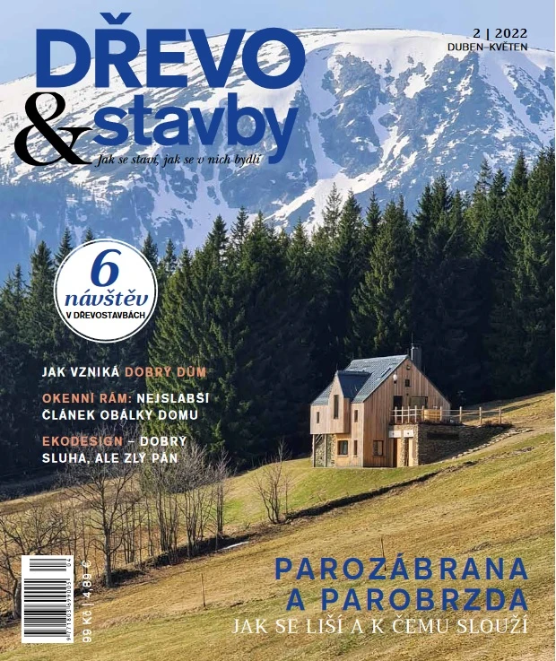 Dřevostavba na svahu s horami v pozadí.