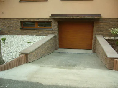 Příklad obložení soklu domu kamenem u garáže s oknem.