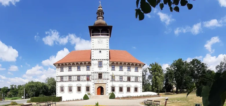 Bílý zámek s keramickou střešní krytinou na modré obloze.