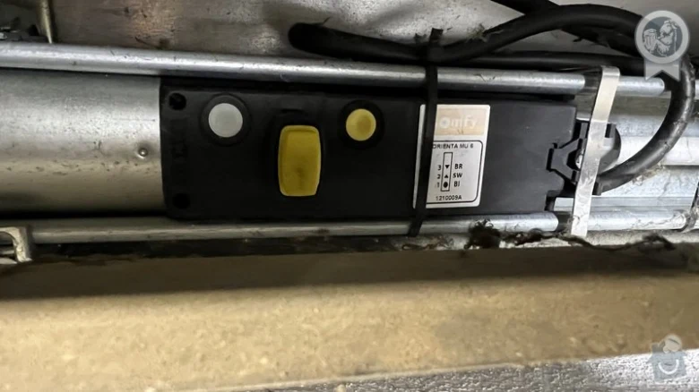 Vnitřní elektronika motoru pro žaluzie s žlutým tlačítkem.