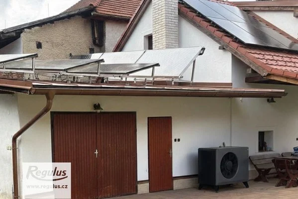 Tepelné čerpadlo a solární panely na střeše domu.